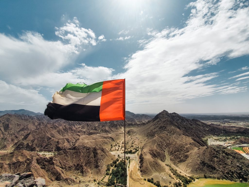 UAE flag with Fujairah mountain landscape
